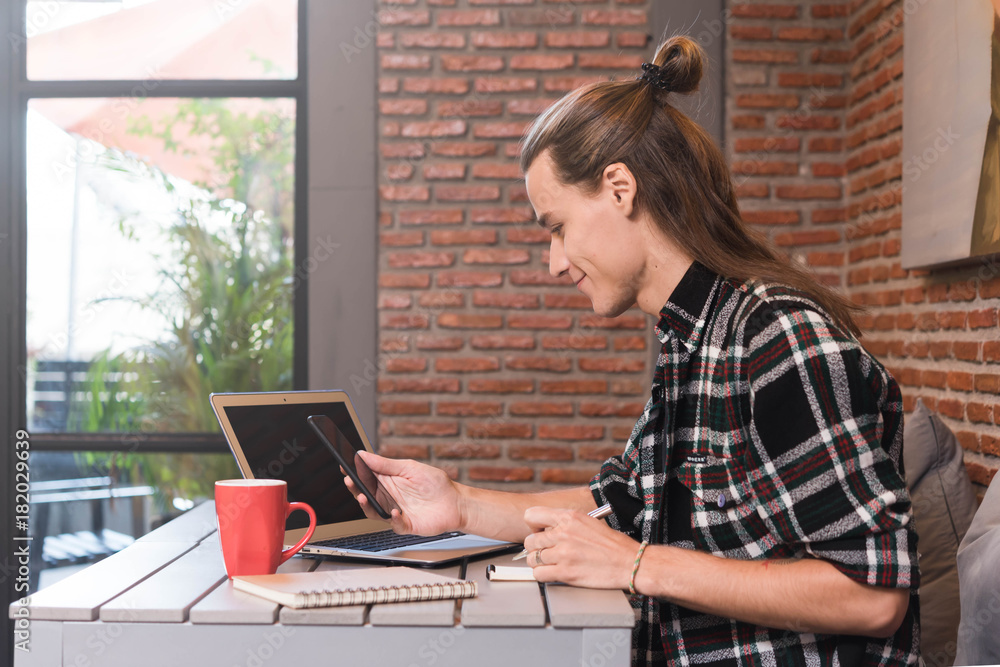 Male freelancer use smartphone and laptop in cafe, nomad worker conceptual