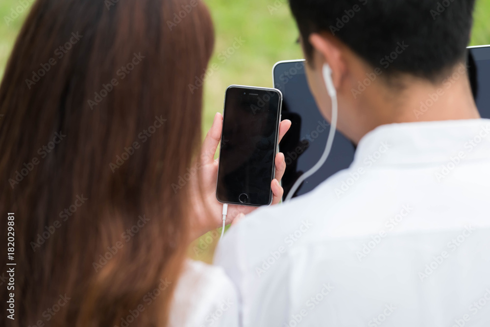 商人和女人在公园里用笔记本电脑和智能手机，一起坐在草地上