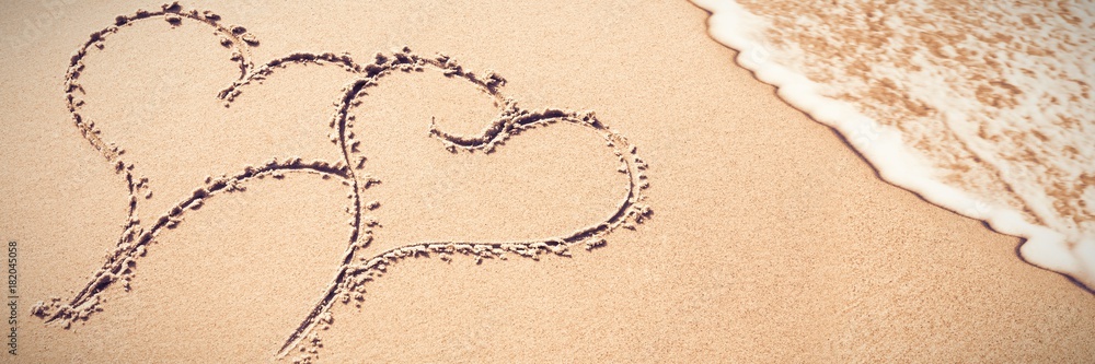 Two heart shapes inscribe on sand