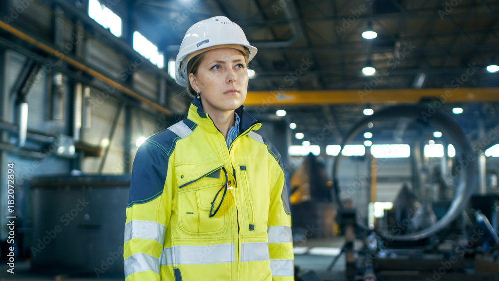 Female Industrial Worker in the Hard Hat Standing in a Middle of a Heavy Industry Manufacturing Fact