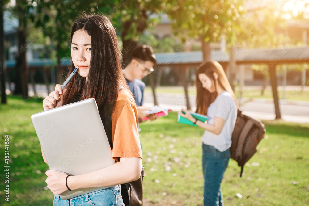 一群年轻或十几岁的亚洲学生在大学里微笑着读着书，看着ta