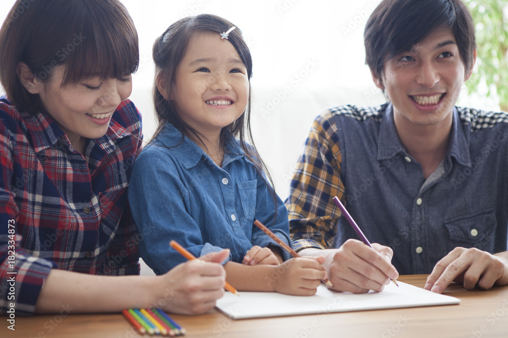 Dad, mommy and daughter are painting with colored pencils.