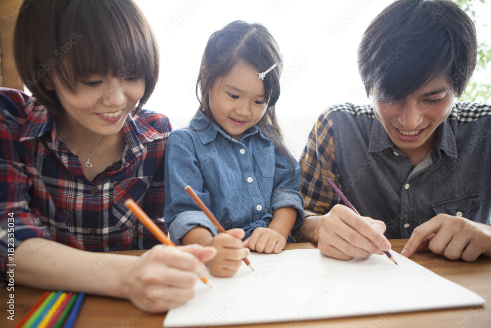 Dad, mommy and daughter are painting with colored pencils.