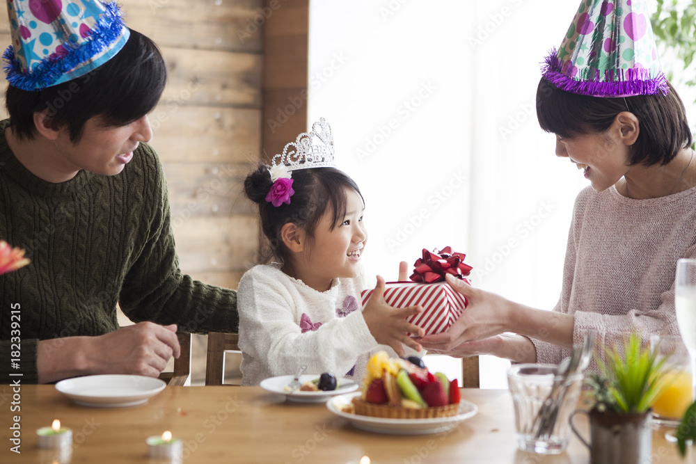 爸爸和妈妈给她女儿送生日礼物。