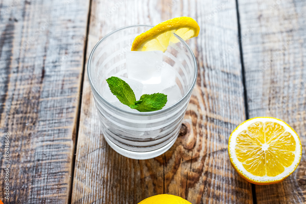 glass with ice and lemon, mint on wooden table