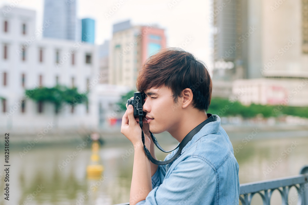 Young asian man tourist taking photos outdoor in the city