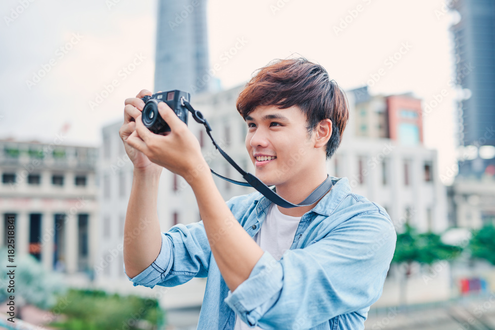 Young asian man tourist taking photos outdoor in the city