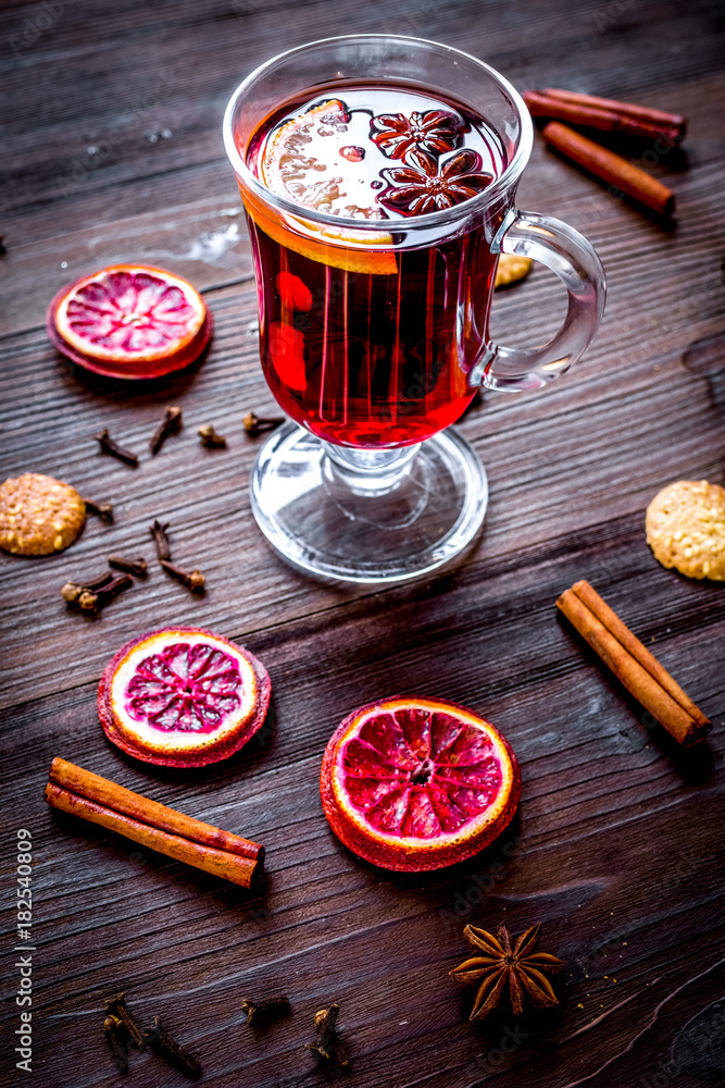 mulled wine with spices in cup on wooden background