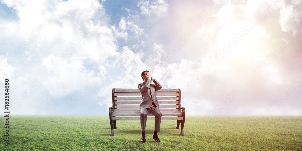 Young man in summer park on bench do not want to see anything