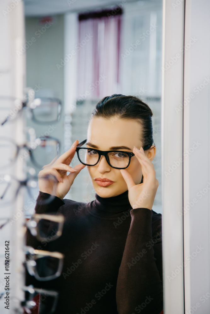 Beautiful girl wearing glasses in optician shop. Eyesight correction. Optics. Emotions. Ophthalmolog