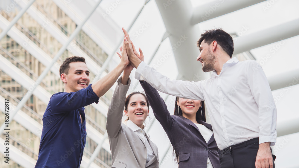 young businessman and businesswoman express teamwork, stacking hands at outdoor office