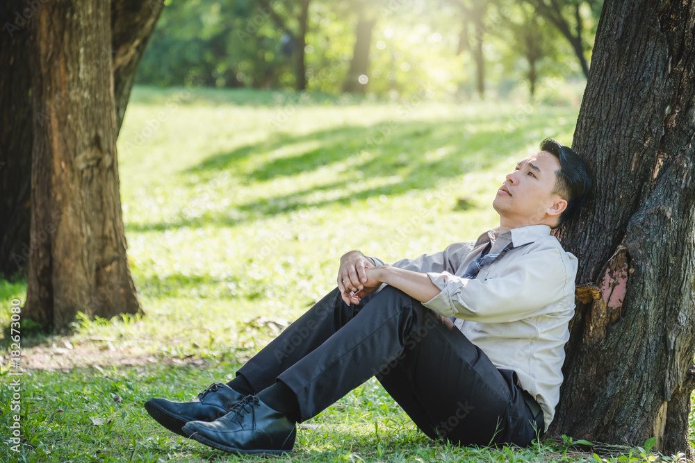 Asian business man sitting at outdoor park, feeling upset/stressed/down/tired/disappoint/exhausted f