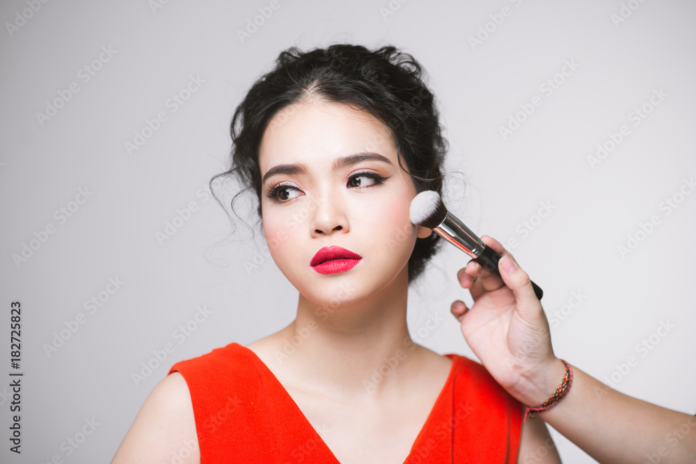 Portrait of attractive asian young adult woman applying blusher