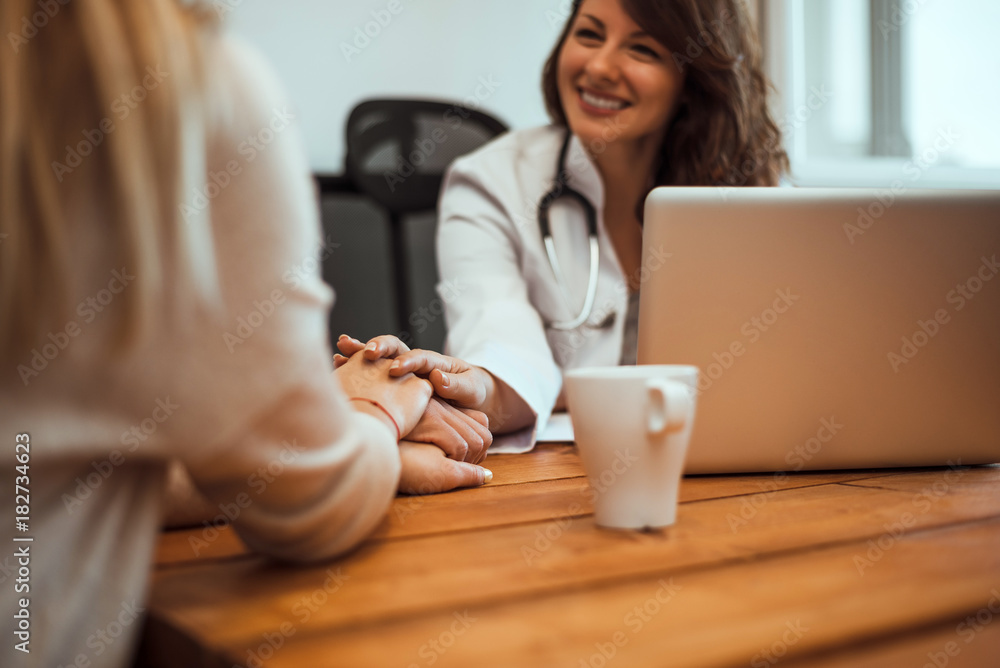 Doctor reassuring his female patient by touching her hands while talking.