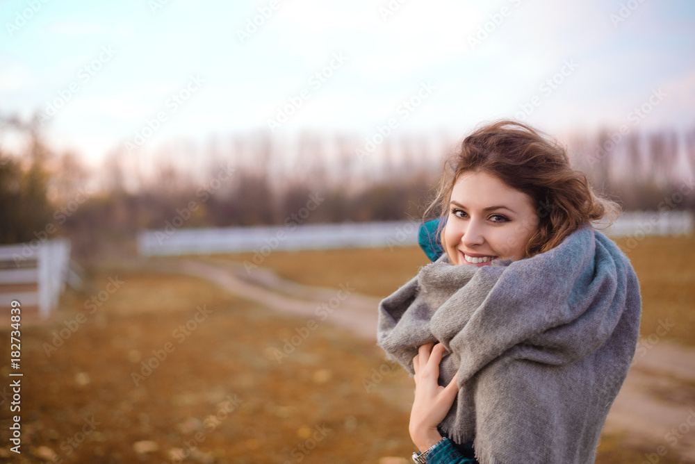 Smiling fashion woman walking in autumn park with warming scarf.