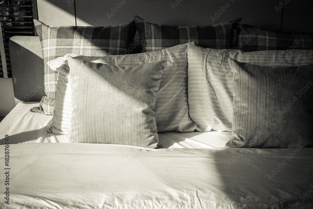 Bed maid-up with clean white pillows and bed sheets in beauty room. Close-up. Lens flair in sunlight