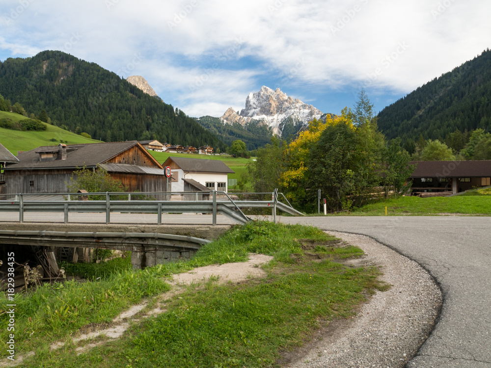 从阿尔卑斯山丘陵和山村背景的低点开始的沥青路。公路旅行co