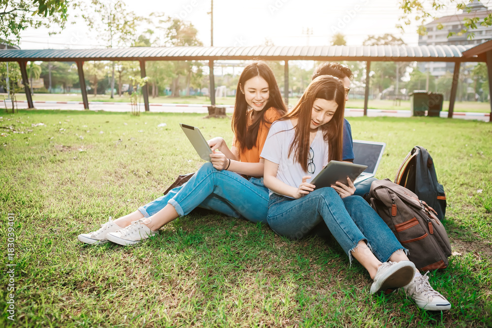 一群年轻或十几岁的亚洲学生在大学里微笑着看书，看着ta