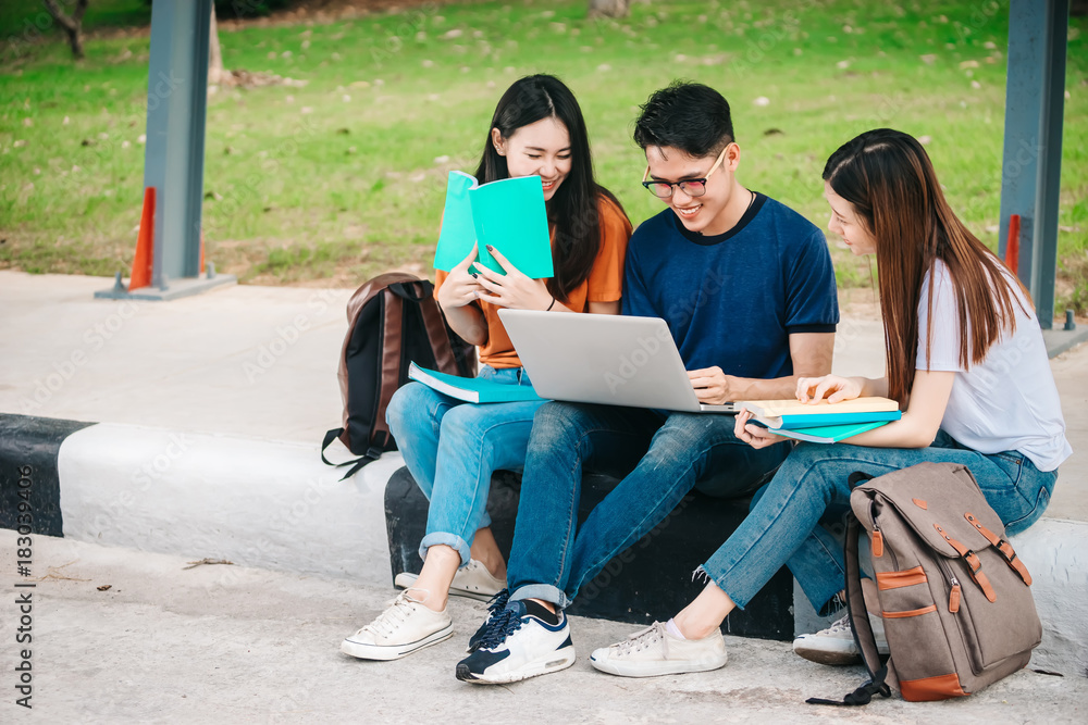 一群年轻或十几岁的亚洲学生在大学里微笑着读着书，看着ta