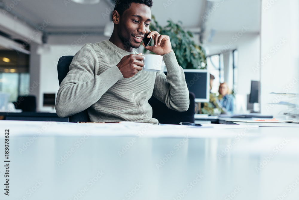 African man talking on mobile phone and drinking coffee