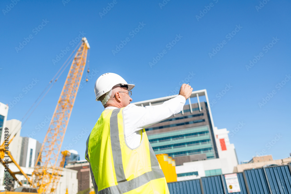 Senior foreman in glasses doing his job at building area on sunny day