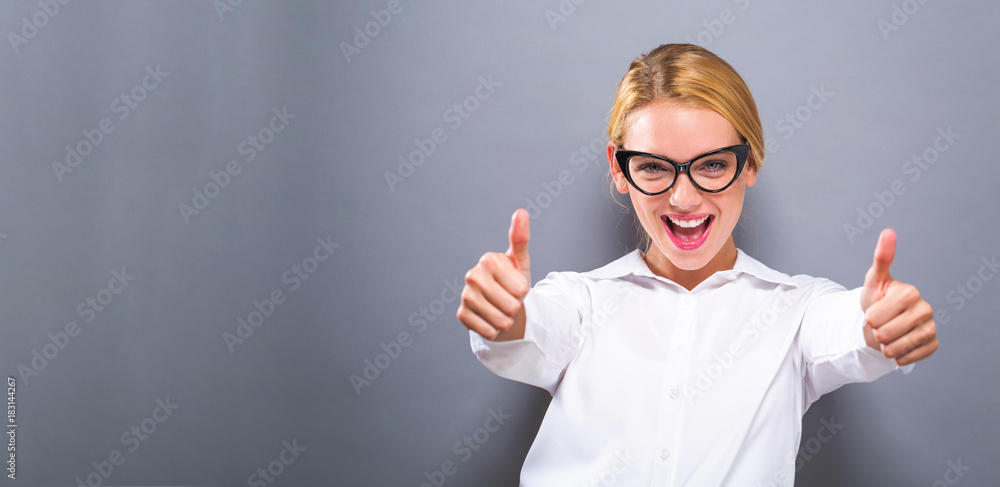 Happy young woman giving thumbs up on a solid background