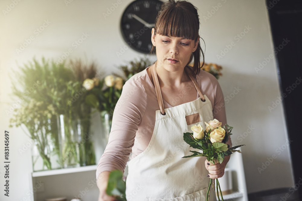 年轻的女花商在她的花店里制作花束