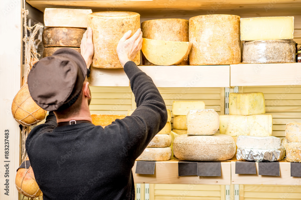 Cheese seller putting goods on the shelves at the cheese store