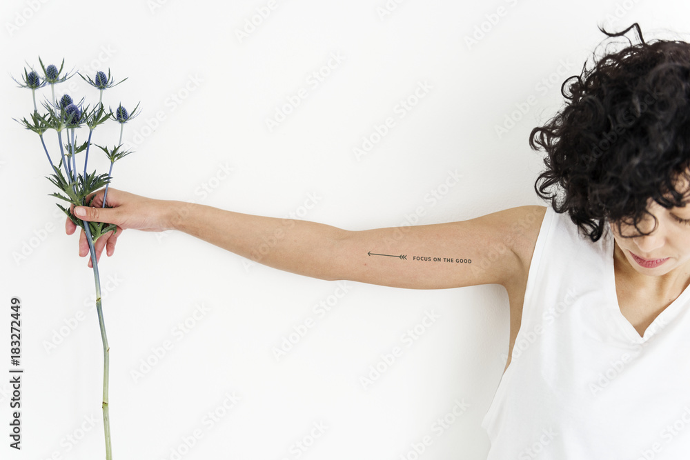 A woman is showing her tattoo on her arm