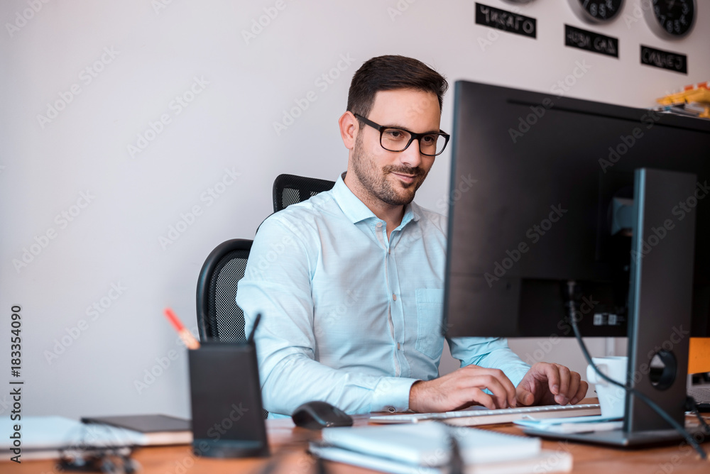 Delighted programmer with glasses using a computer.