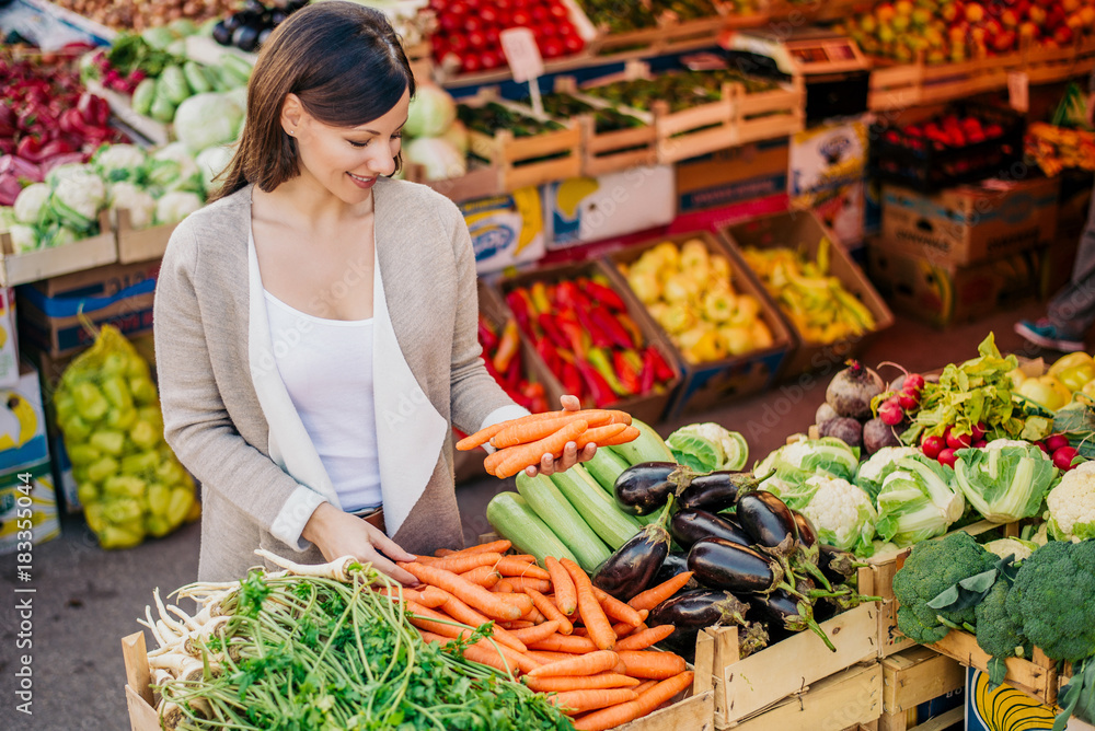 View at young woman buying vegetables at the market.