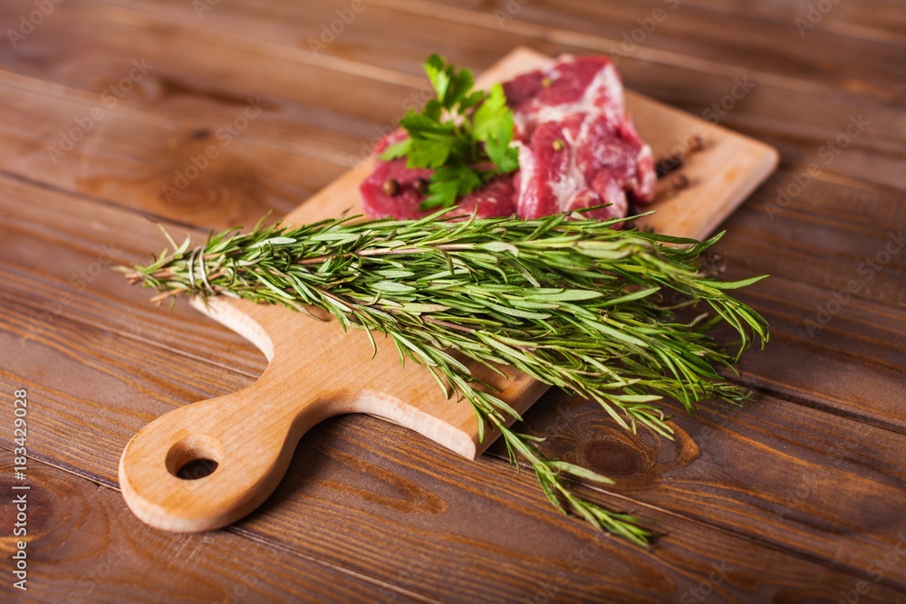 Raw Meat with Rosemary on a Cutting Board