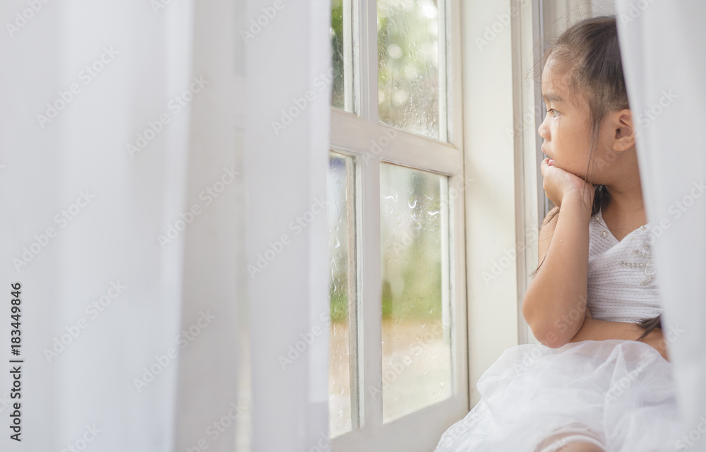 Depressed Little girl near window at home