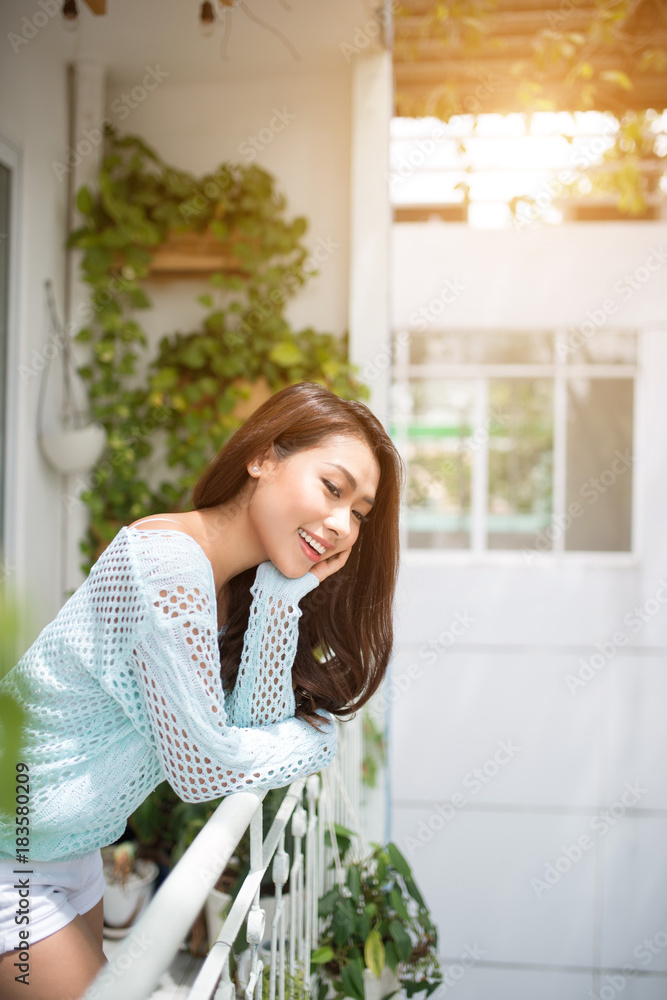 Young asian woman relaxing on a balcony  enjoying fresh air.