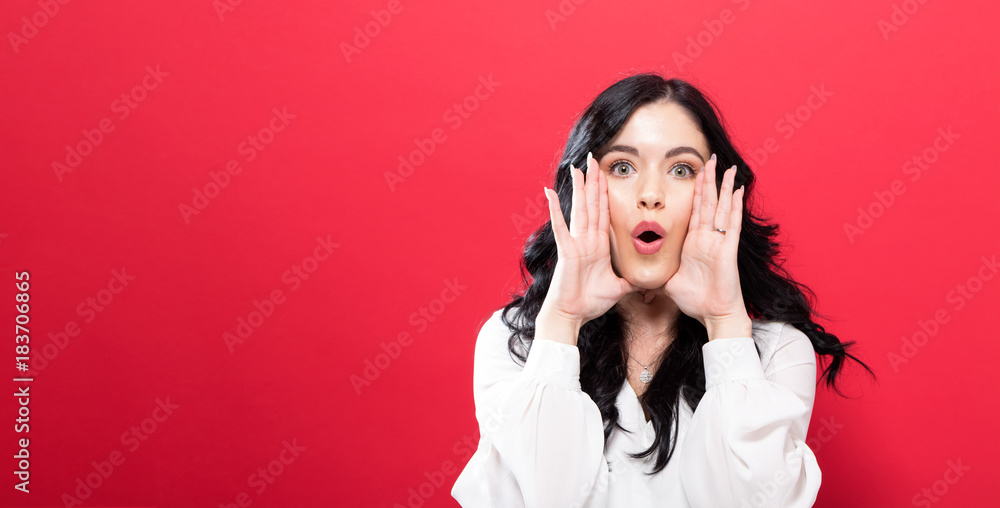 Young woman shouting an annoucment on a solid background