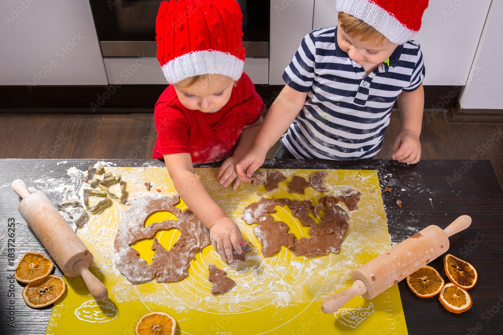 Cute little boy and girl twins preparing Christmas cookies in the kitchen