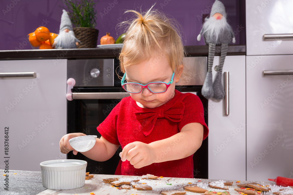 Cute little girl decorating Christmas cookies with sugar icing