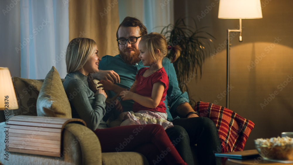 Long Shot of a Father, Mother and Little Girl Watching TV. Father Explains Something to His Little G