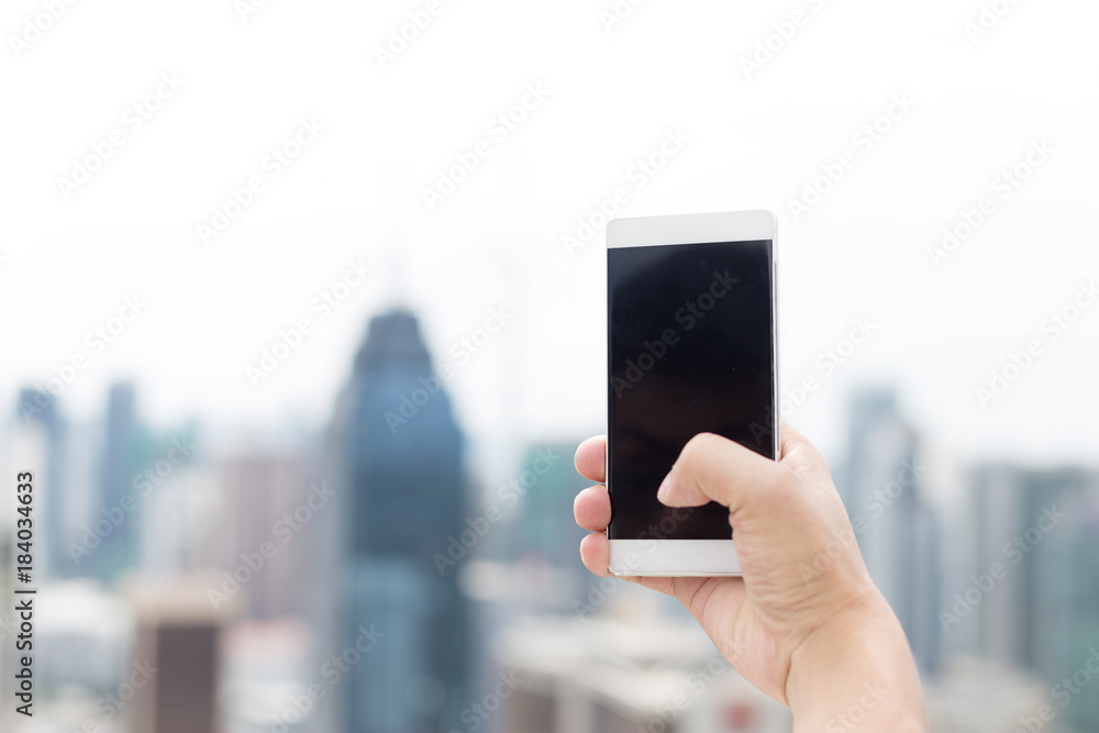 mans hand with mobile phone in modern city