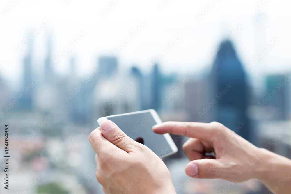 mans hand with mobile phone in modern city