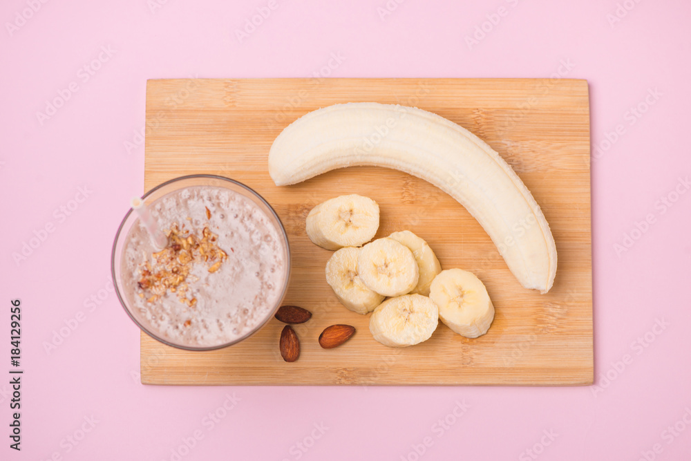 Fresh made banana smoothie in a glass on pink background