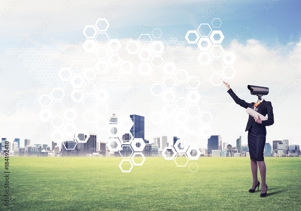 Camera headed woman standing on green grass against modern citys