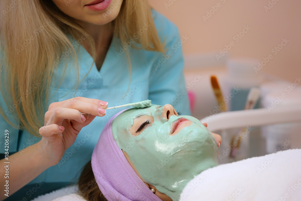 Cleansing face mask with hyaluronic acid. Woman receiving cosmetic procedure in beauty salon.