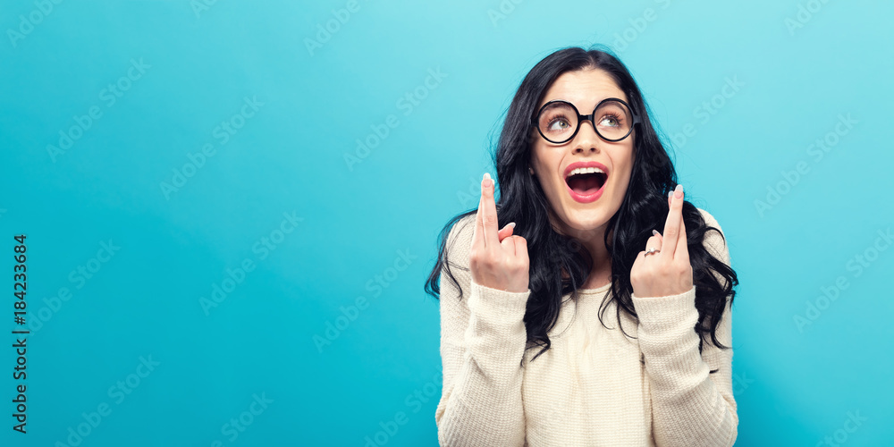 Young woman crossing her fingers and wishing for good luck