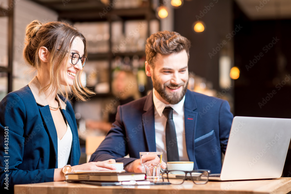 Caucasian business couple dressed strictly in the suits working together with laptop and paper chart