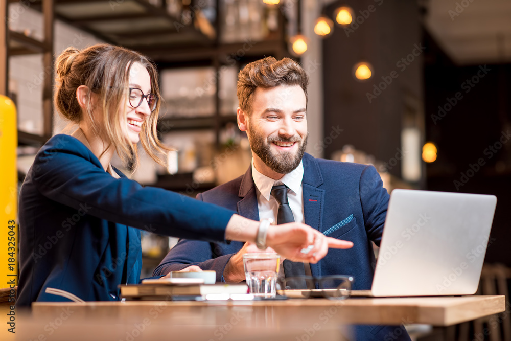 Caucasian business couple dressed strictly in the suits working together with laptop and paper chart