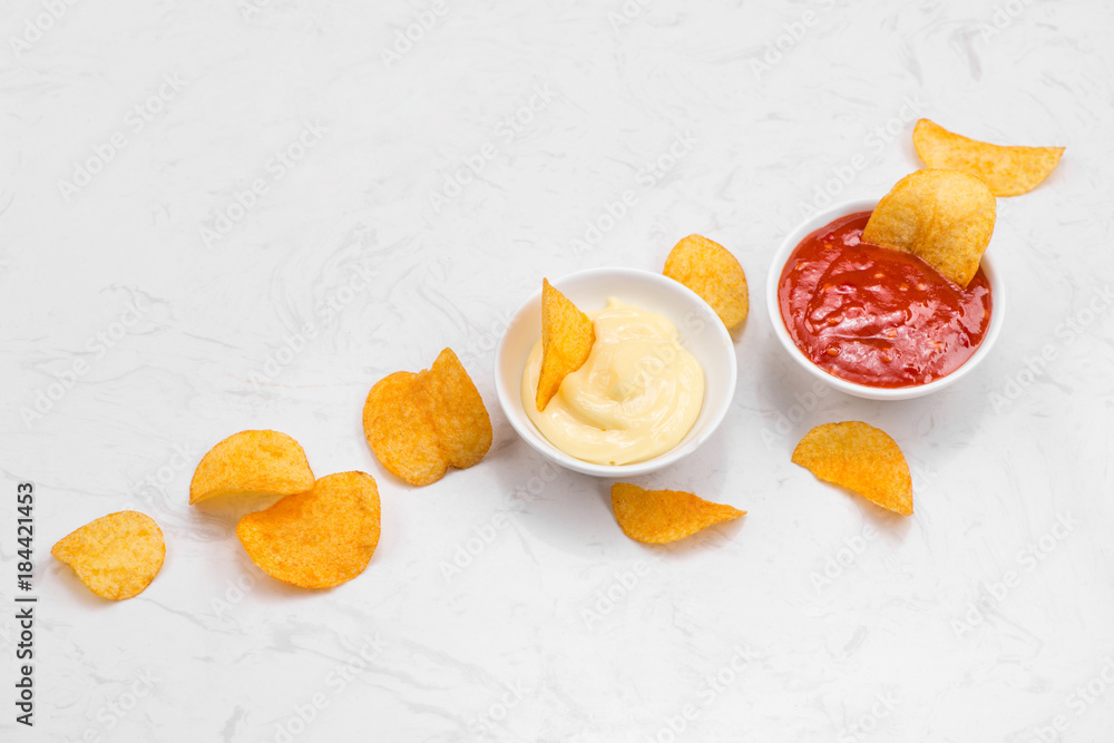 Concept of unhealthy food. Heap of potato crisps and ketchup and mayonnaise