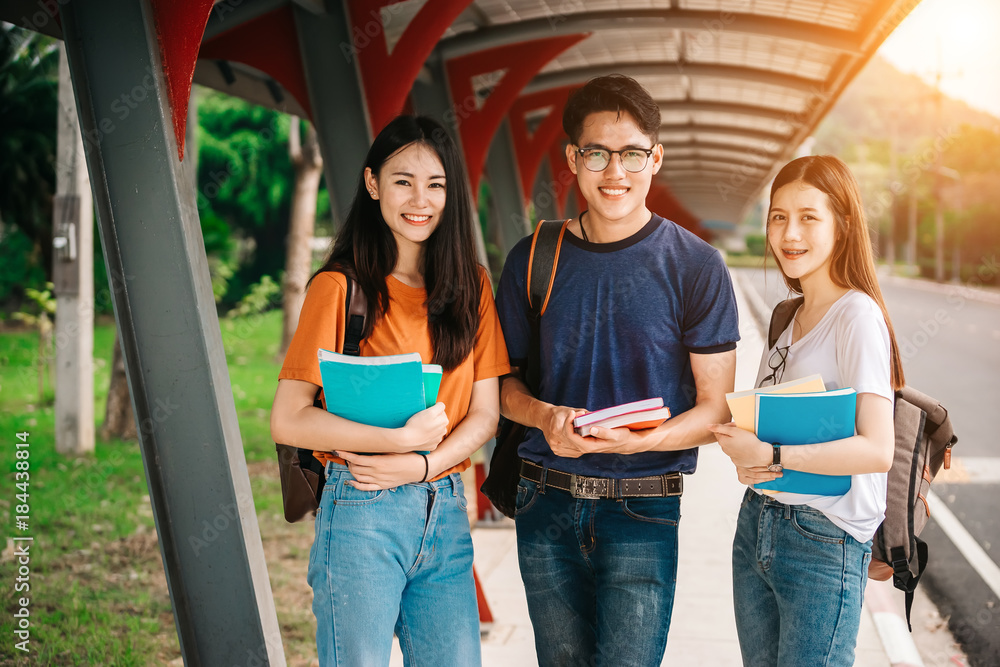 一群年轻或十几岁的亚洲学生在大学里微笑着读着书，看着ta