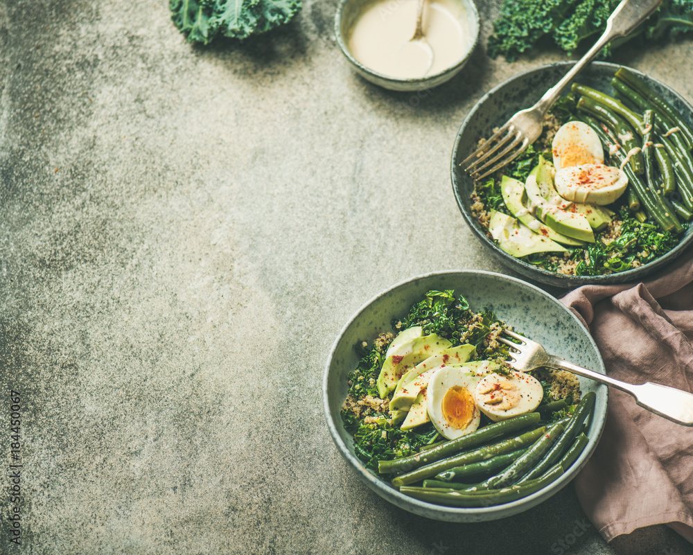 Healthy vegetarian breakfast bowls. Quinoa, kale, green beans, avocado, egg and tahini dressing bowl