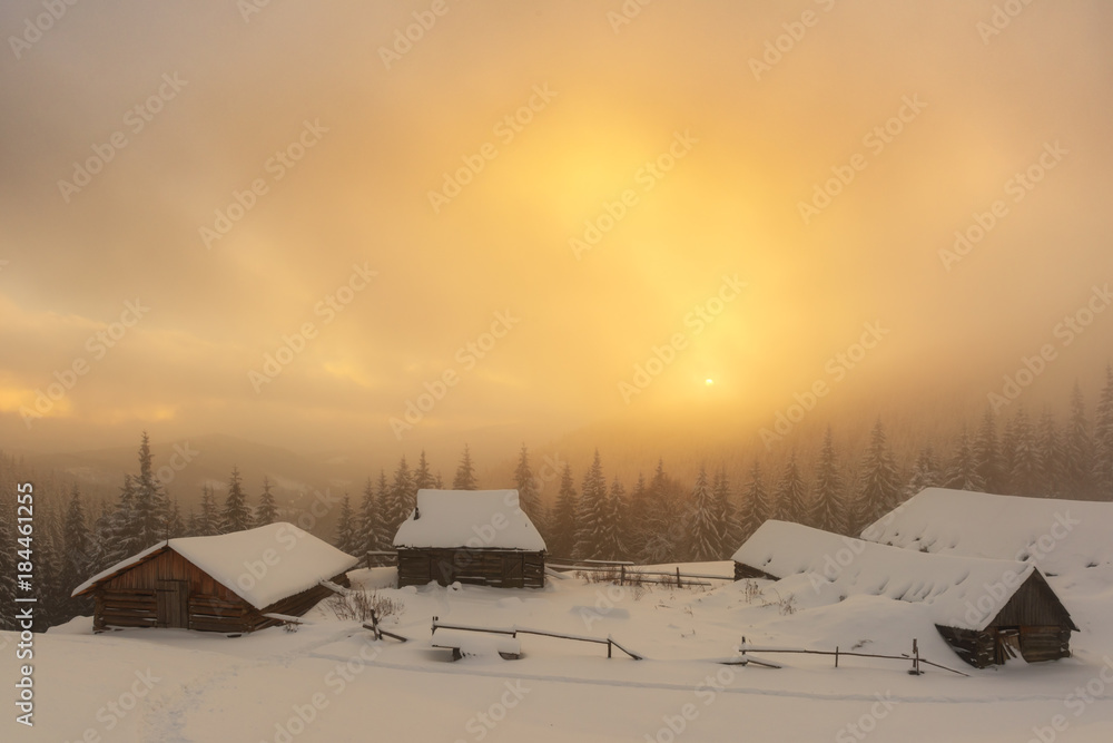 阳光照耀下的雪山中令人惊叹的橙色冬季景观。前景上的木屋